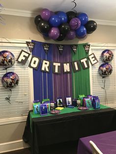 a table with purple, green and blue balloons on it at a fortnite party