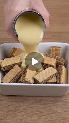 a person pouring cream over crackers in a bowl