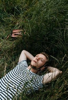 a man laying in the grass with his eyes closed