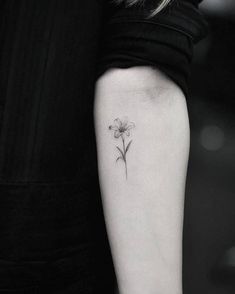 a woman's arm with a small flower tattoo on the left side of her arm