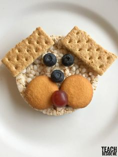 a close up of a plate of food with crackers and fruit on it that looks like a face