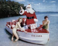 two women in swimsuits and santa clause on a boat with gifts for the holiday season