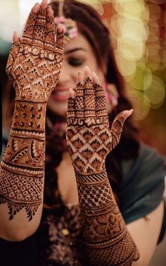 a woman holding her hands up to show the hendi