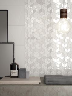 a white tiled wall with a light bulb hanging from it's side and towels on the counter