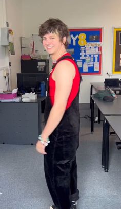 a young man standing in an office wearing black and red