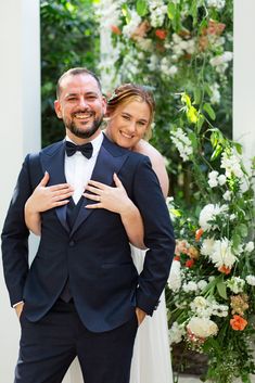 a man in a tuxedo is hugging a woman's shoulder and smiling