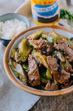 a bowl filled with meat and peppers next to rice