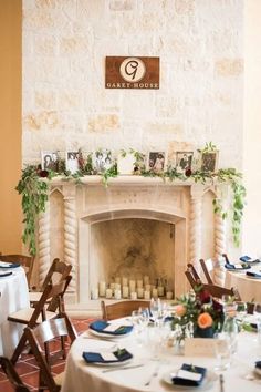 a room with tables and chairs set up for a formal function in front of a fire place