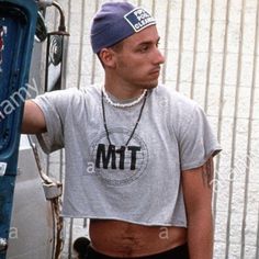 a man with tattoos on his chest standing in front of a truck - stock image