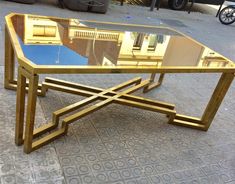 a glass table sitting on the ground in front of a building with an iron frame