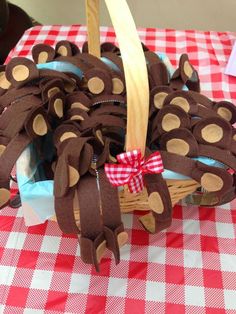 a basket filled with brown teddy bears sitting on top of a red and white checkered table