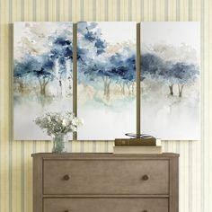 two paintings are hanging on the wall above a dresser with flowers in front of it