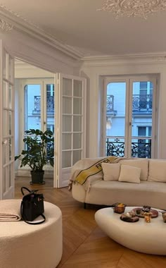 a living room filled with white furniture and lots of window sill space next to a plant