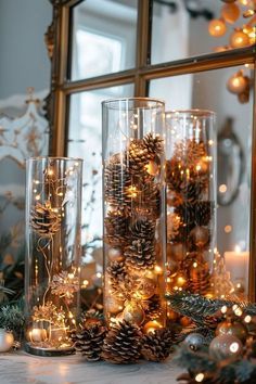 christmas decorations and pine cones are displayed in front of a mirror with lights on it