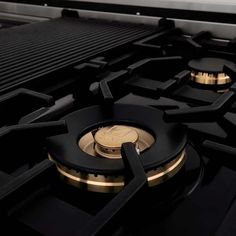 a close up view of the burners and controls on a black stove top with gold trim