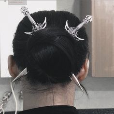 a woman with hair pins in her hair is looking at the mirror and has scissors on her head