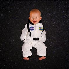 a baby dressed in an astronaut's suit is smiling at the camera with stars behind him