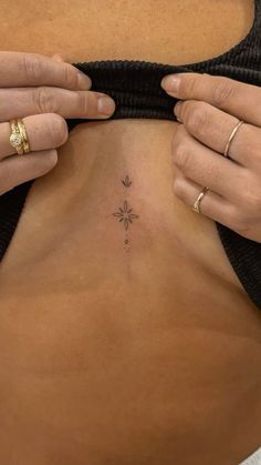 a woman is showing off her stomach with small tattoos on the side and chest area