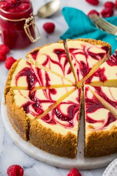 a cheesecake with raspberry sauce is cut into slices