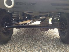 the front end of a vehicle with two rear axles on graveled area next to trees