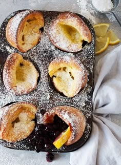 lemon and blueberry pastries in a muffin tin with powdered sugar on top