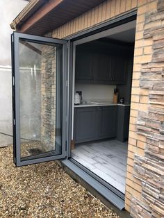 an open patio door on the side of a house with wood flooring and stone walls