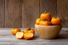 a wooden bowl filled with oranges on top of a table