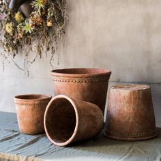 three clay pots sitting on top of a table next to a wreath and wall hanging