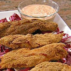 fried fish with coleslaw and dipping sauce on a white platter next to a glass bowl