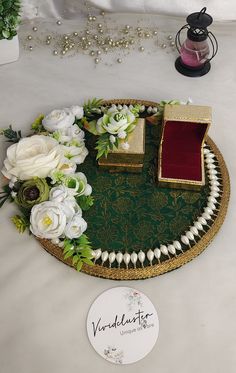 there is a tray with flowers and jewelry on the table next to a card box