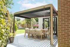 an outdoor dining area with table and chairs under a pergolated roof on a sunny day