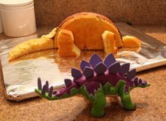 an orange stuffed animal laying on top of a table next to a purple flower plant