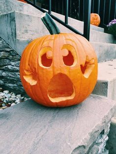 a carved pumpkin with an angry face on it's front step, sitting in front of a set of steps