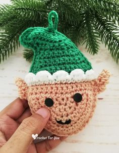 a crocheted christmas ornament with a green hat on it's head