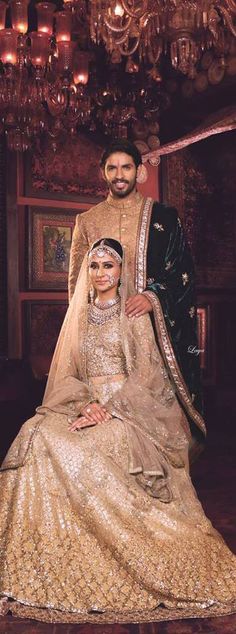 the bride and groom pose for a photo in their traditional wedding outfits, with chandeliers hanging from the ceiling