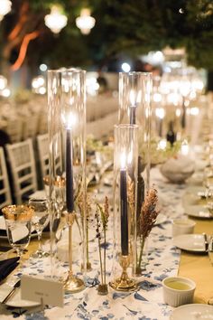 the table is set with candles, plates and silverware for an elegant dinner party