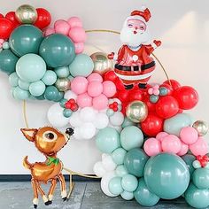 a balloon arch with santa claus and rudolph on it, surrounded by balloons in various colors