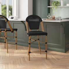 two black chairs sitting next to each other on top of a hard wood floor in a kitchen