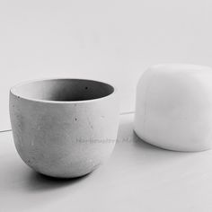 a white bowl sitting on top of a table next to a square object in black and white