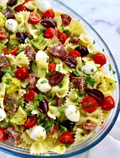 pasta salad with tomatoes, olives, and mozzarella in a glass bowl