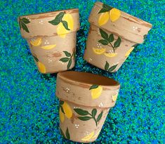 three wooden planters with lemons painted on them sitting on blue glittered ground