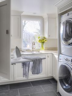 a washer and dryer in a white kitchen with gray tile flooring on the walls