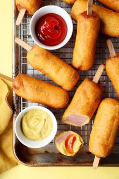 some food is laying out on a tray with toothpicks and dipping sauces