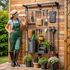 a woman standing in front of a garden shed with gardening tools on the wall behind her