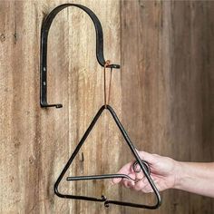 a hand holding a black metal object on top of a wooden wall