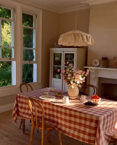 a dining room with a table and chairs in front of a window that looks out onto the woods