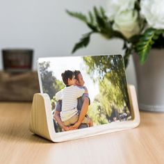 a wooden frame with a photo on it sitting on a table next to a potted plant