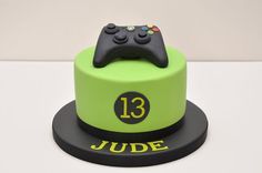 a green cake with a black controller on top that reads 13 june and the number thirteen