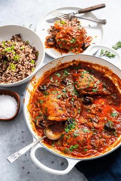 two bowls filled with food next to rice and spoons on a white counter top