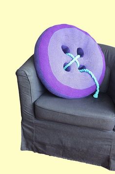 a purple pillow sitting on top of a gray chair